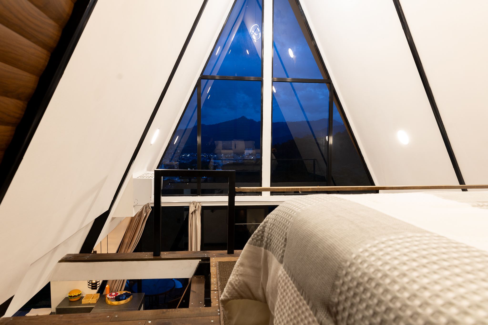Cama del loft frente al ventanal triangular con vista a las montañas
